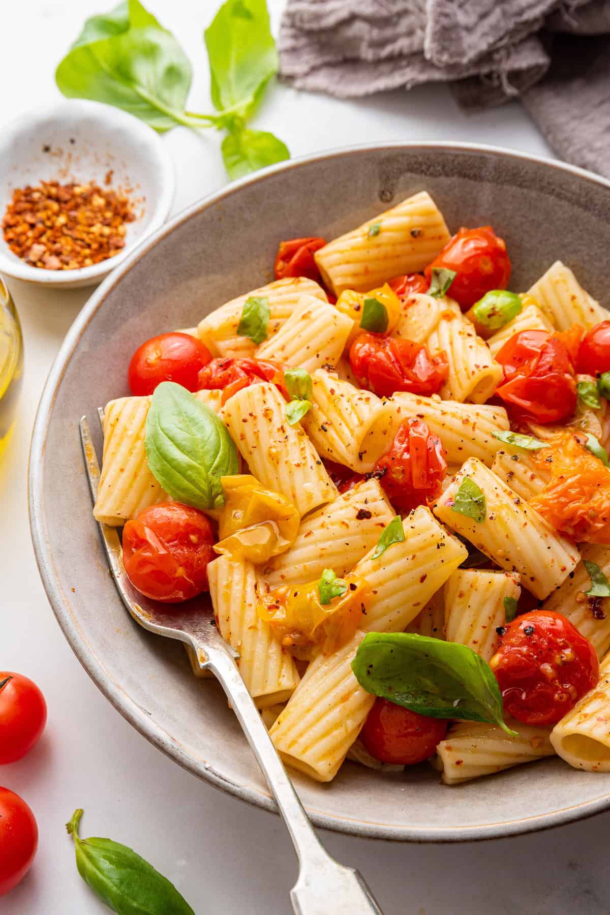 Cherry tomato pasta in bowl, garnished with fresh basil leaves