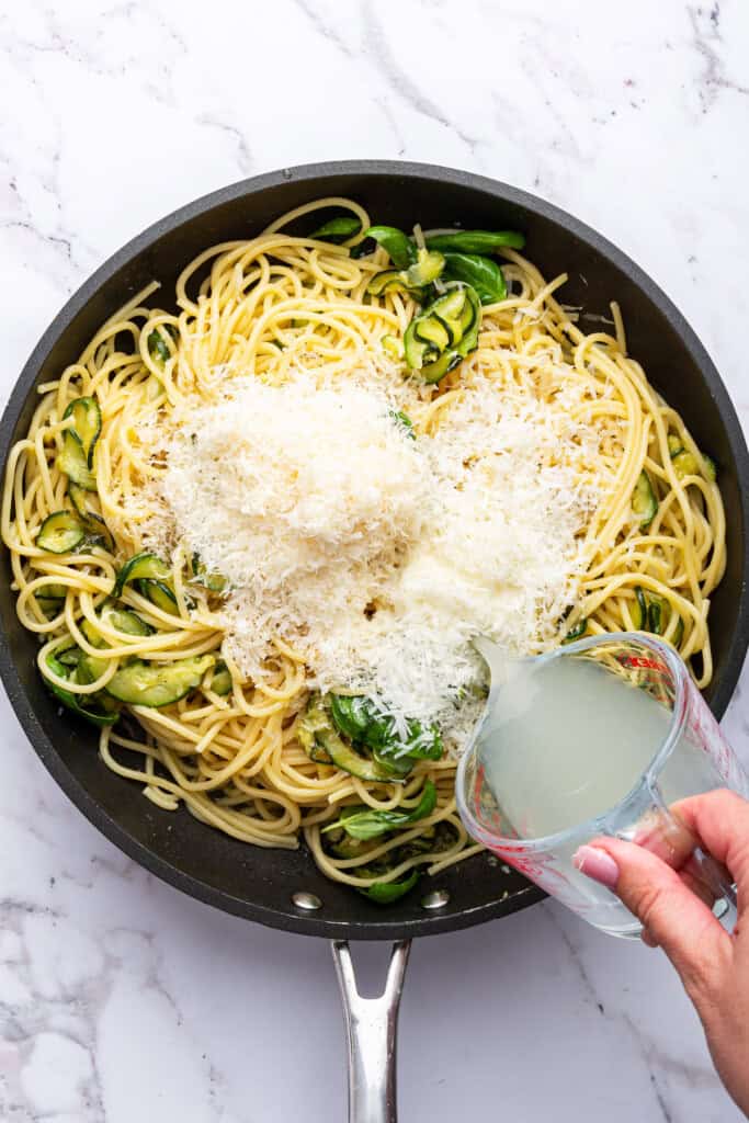 Adding cheese and pasta water to spaghetti alla Nerano in skillet