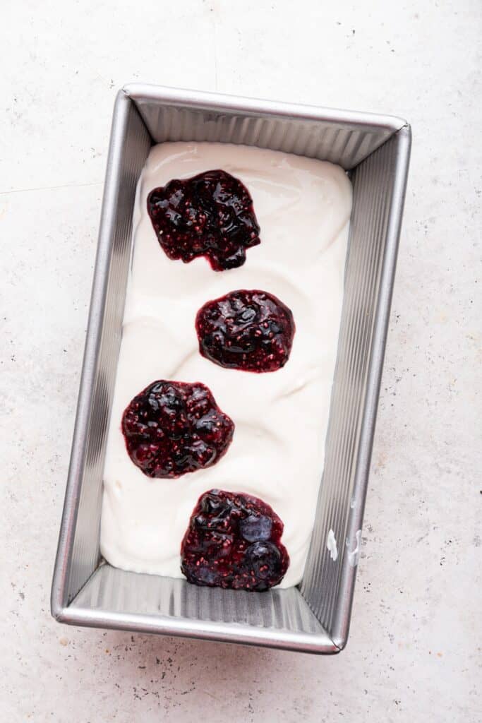 Overhead view of dollops of berry mixture added to cottage cheese ice cream mixture