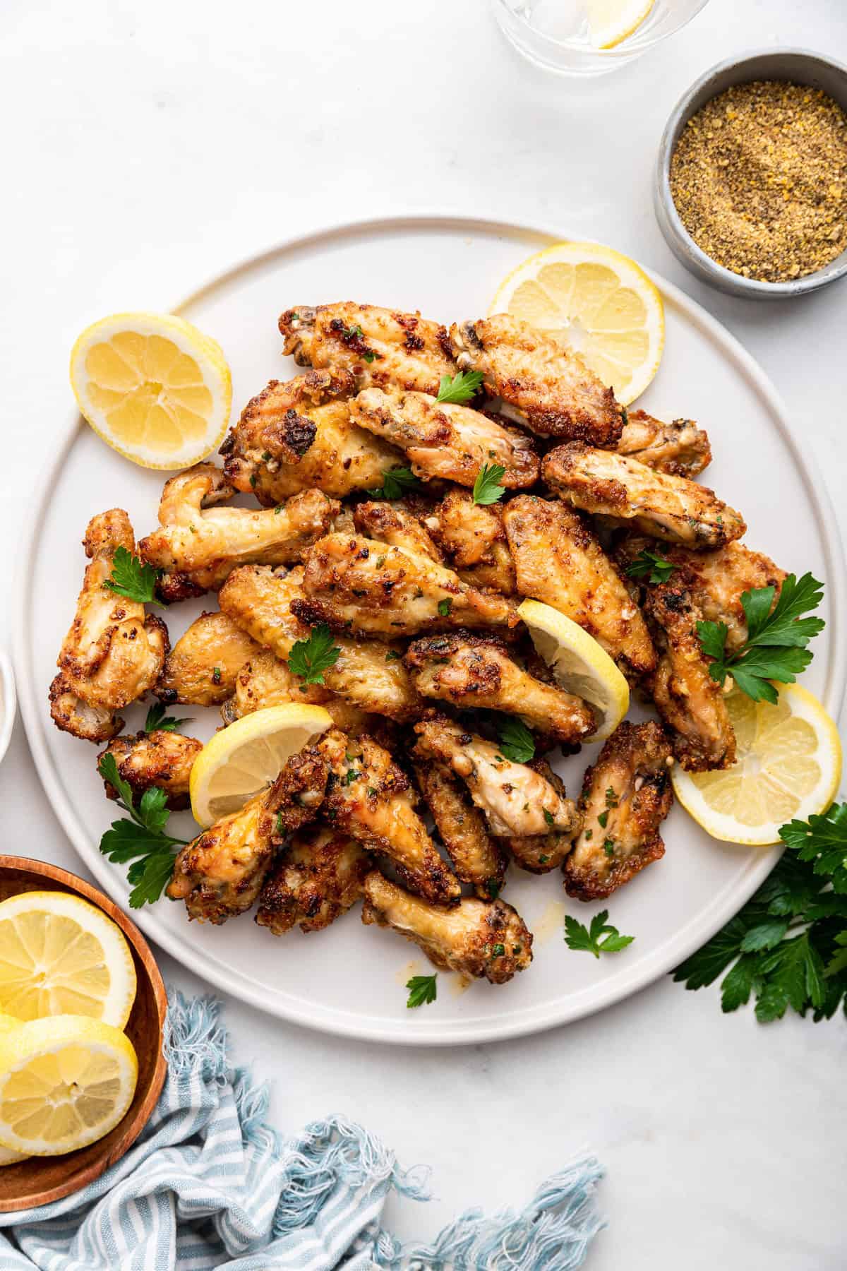 Overhead view of lemon pepper wings on large plate with lemon wedges and parsley