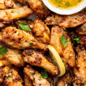 Overhead view of lemon pepper chicken wings with bowl of sauce