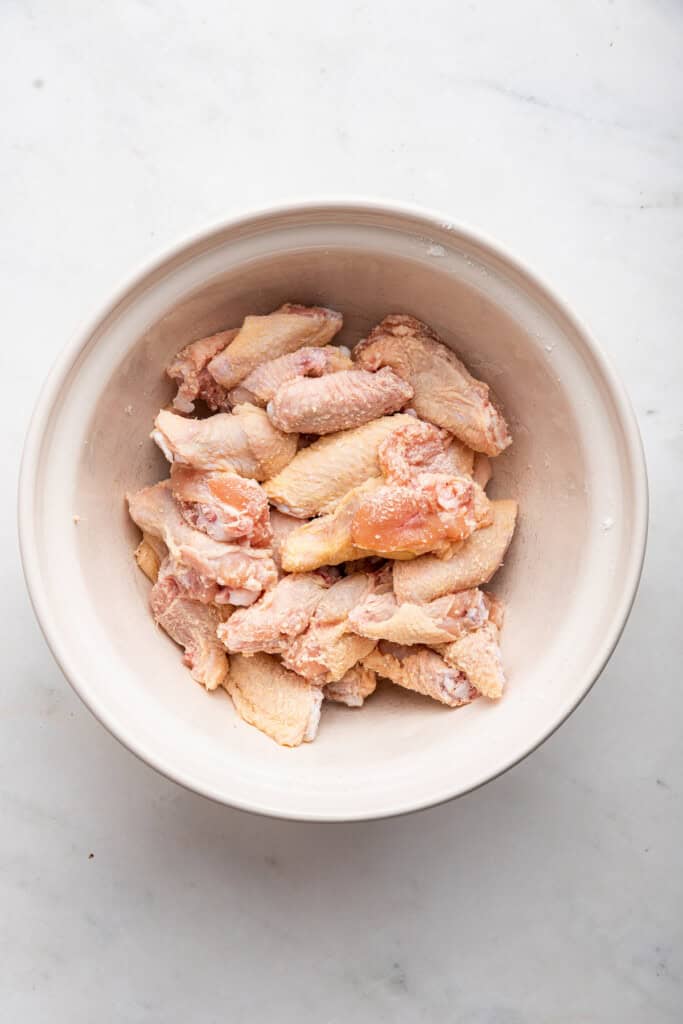 Overhead view of chicken wings in mixing bowl