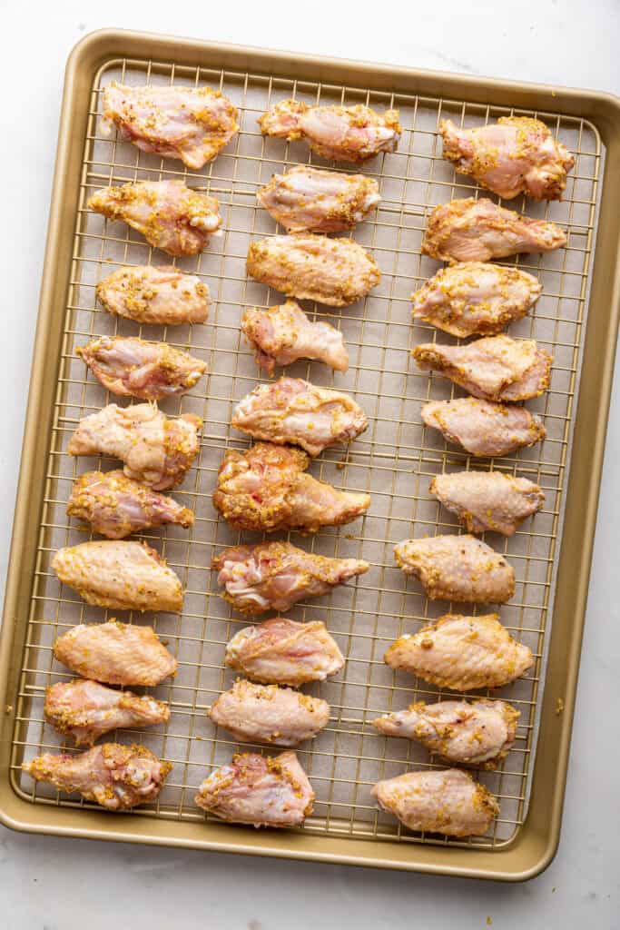 Overhead view of uncooked chicken wings on wire rack