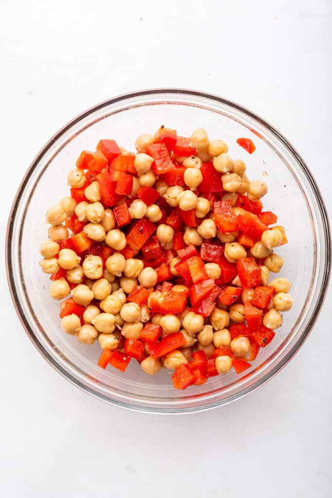 Overhead view of chickpeas and red peppers in glass bowl