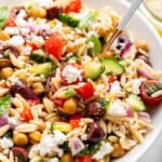 Spoon digging into serving bowl of orzo pasta salad