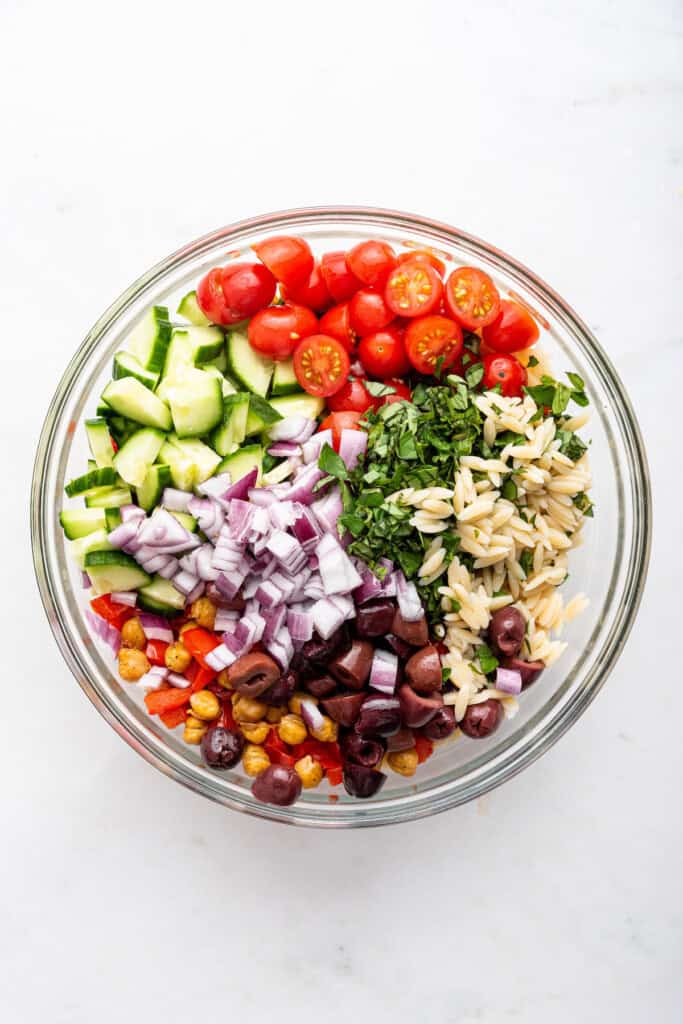 Overhead view of ingredients for orzo pasta salad in bowl