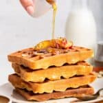 Pouring maple syrup onto stack of high protein waffles