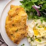 Overhead view of crispy garlic Parmesan chicken on plate with mashed potatoes and salad