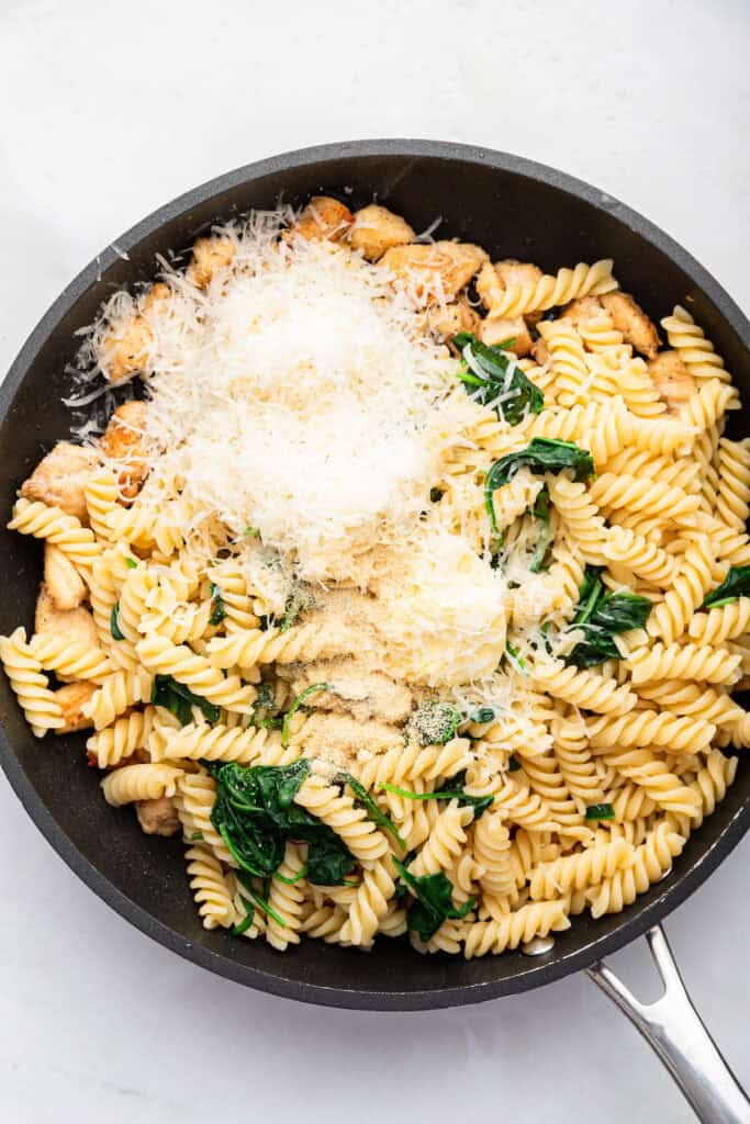 Overhead view of cheese and butter added to garlic Parmesan chicken pasta