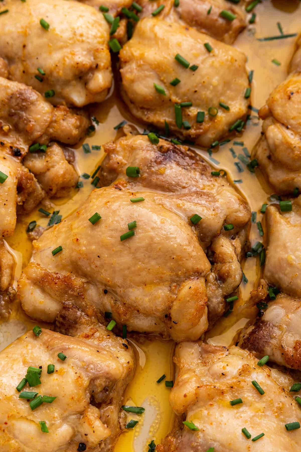 Closeup of juicy baked boneless chicken thighs in baking dish