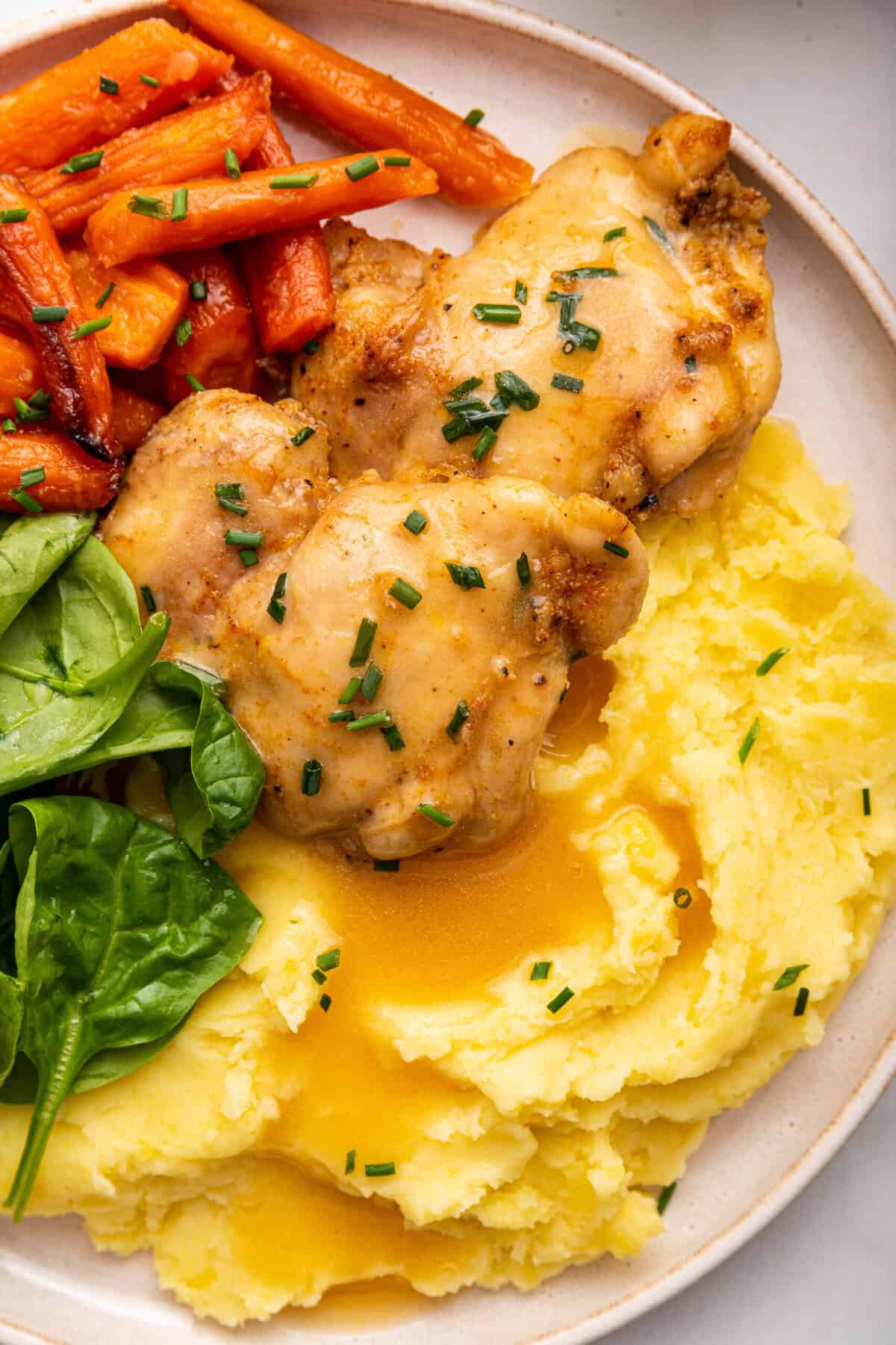 Overhead view of dairy-free mashed potatoes on plate with chicken thighs and carrots