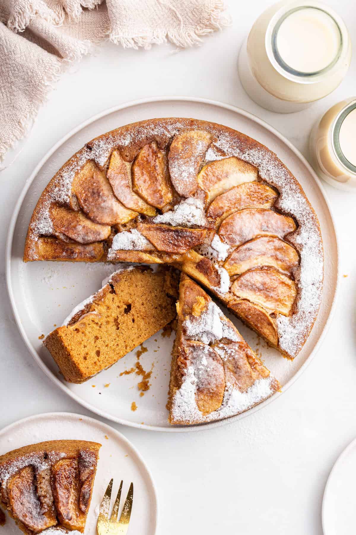 Overhead view of sliced apple cake with one slice turned to show tender, fluffy texture