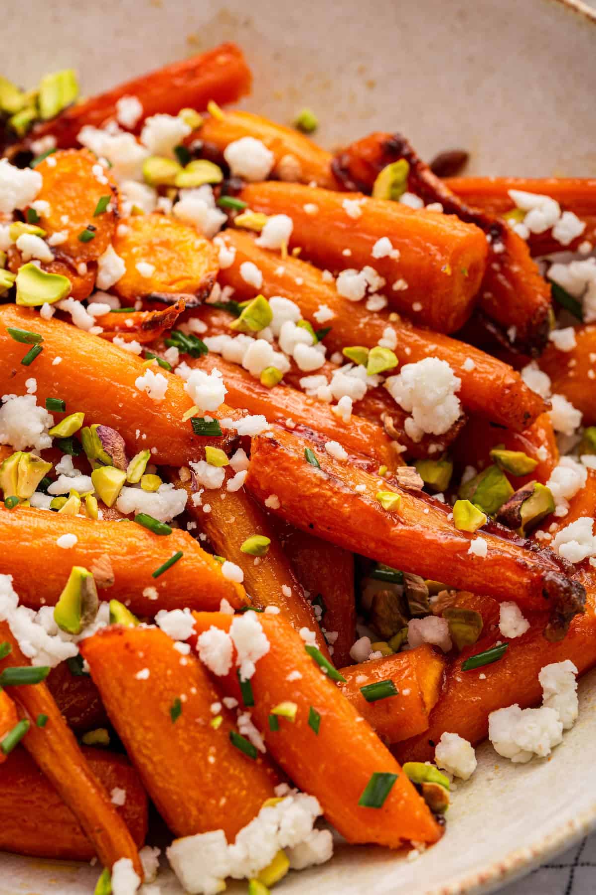 Closeup of honey roasted carrots with goat cheese, chives, and pistachios