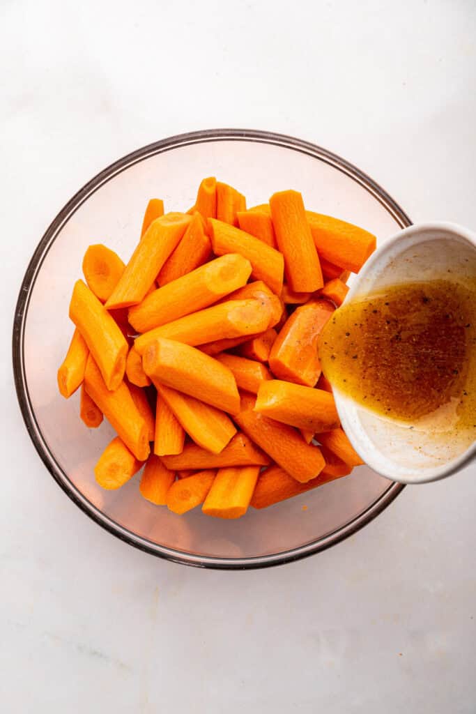 Pouring glaze into bowl of carrots