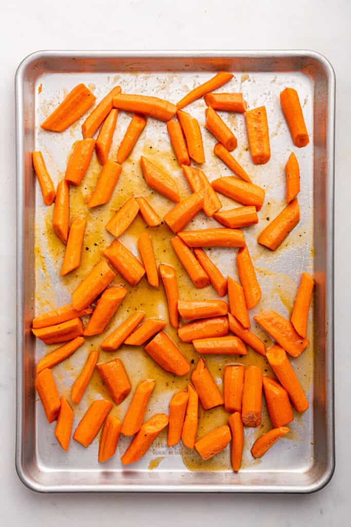 Overhead view of carrots and honey glaze on pan before cooking