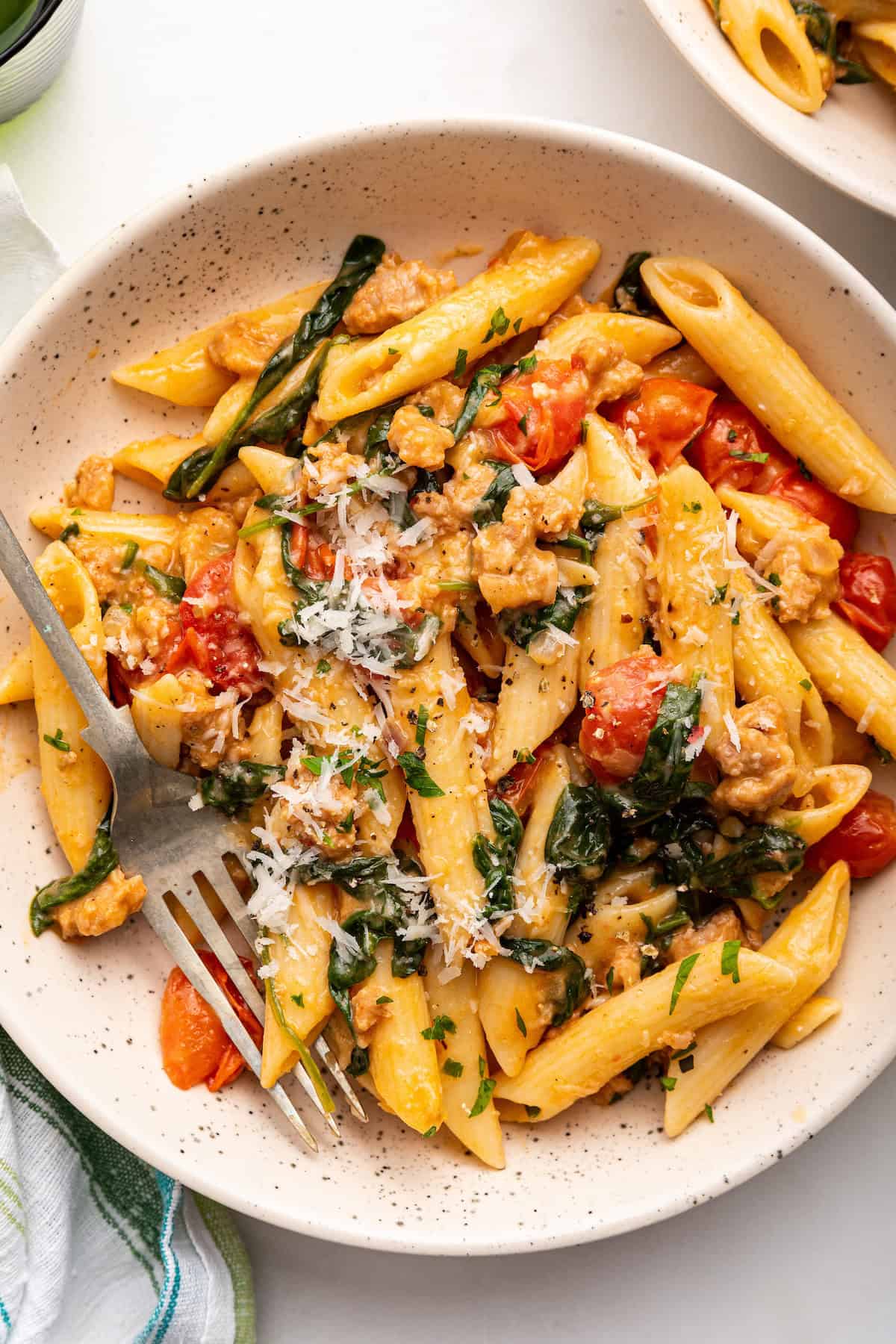 Bowl of sausage pasta with spinach and cherry tomatoes