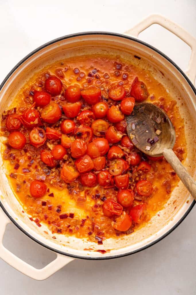 Cherry tomatoes cooking in pan with garlic and red onions