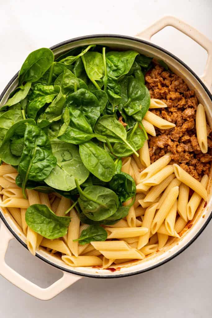 Spinach, sausage, and pasta added to skillet