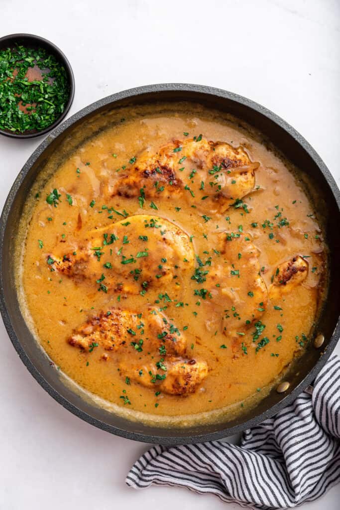 Overhead view of smothered chicken in skillet