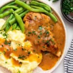 Plate of smothered chicken with mashed potatoes and green beans