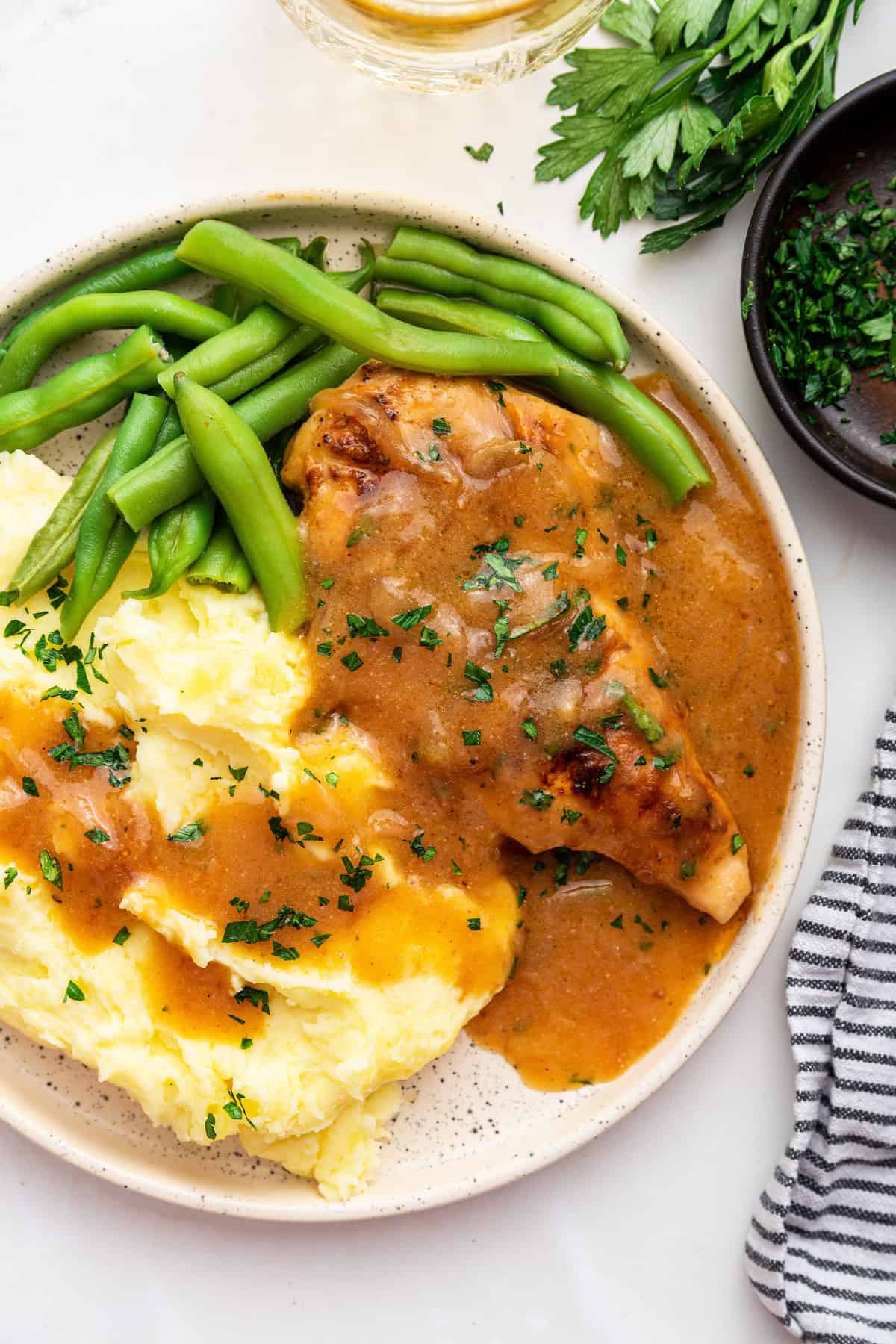 Plate of smothered chicken with mashed potatoes and green beans