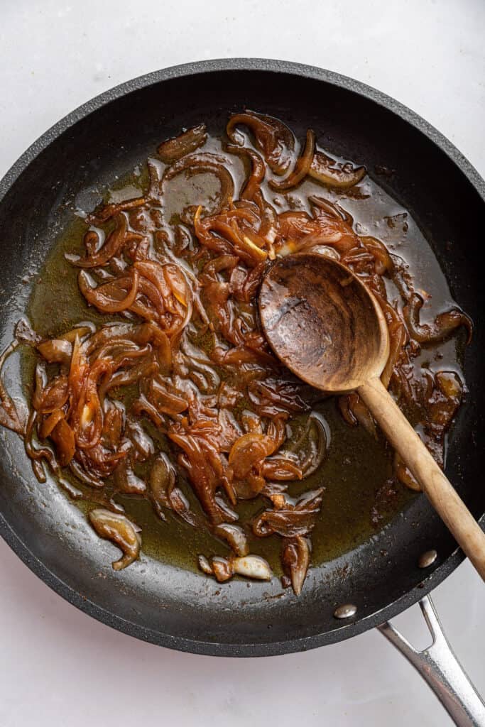 Caramelized onions in skillet with wooden spoon