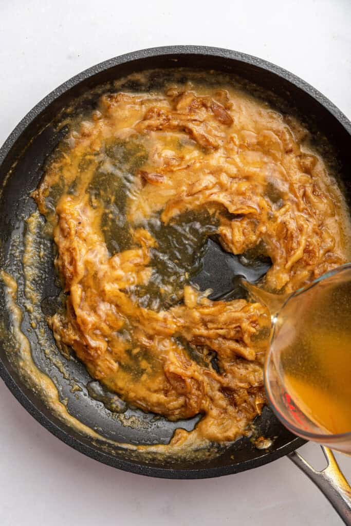 Pouring broth into pan of caramelized onions and flour