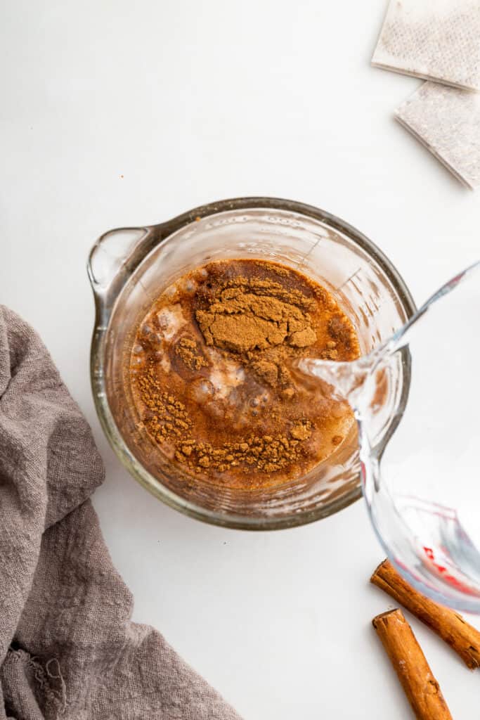 Pouring boiling water into measuring cup with spices and honey