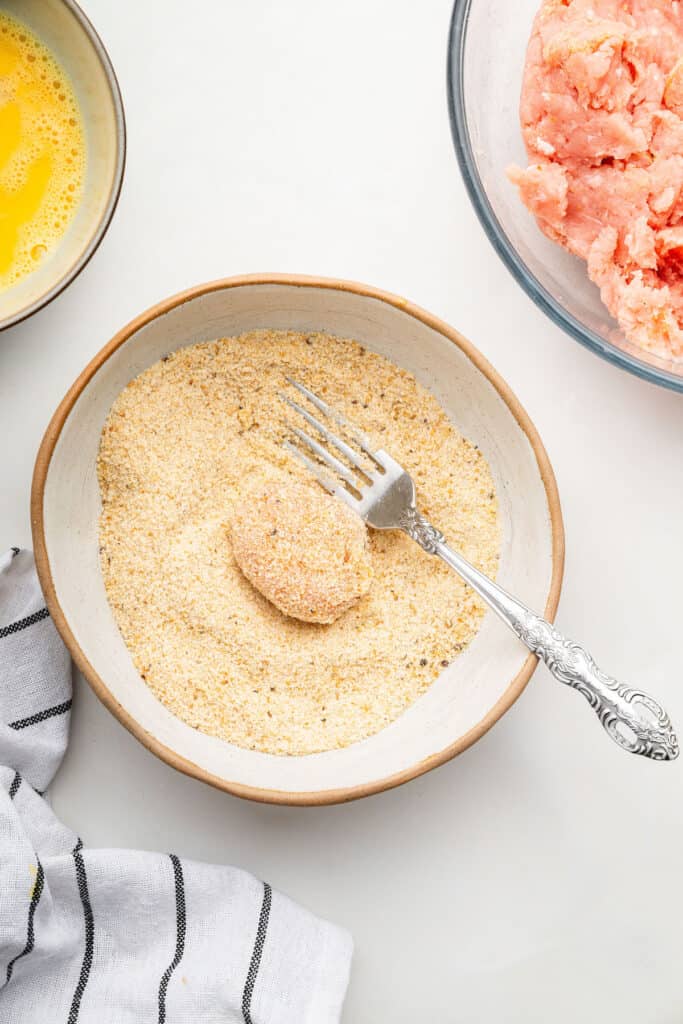 Coating chicken nugget in breadcrumbs