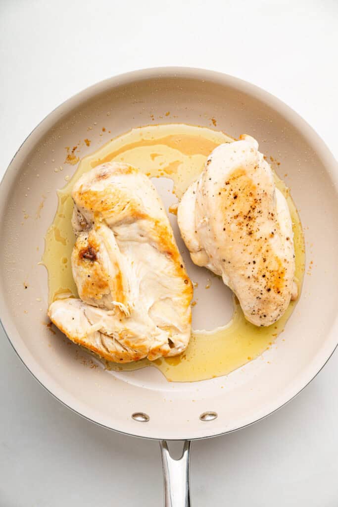 Chicken breast cooking in pan with oil