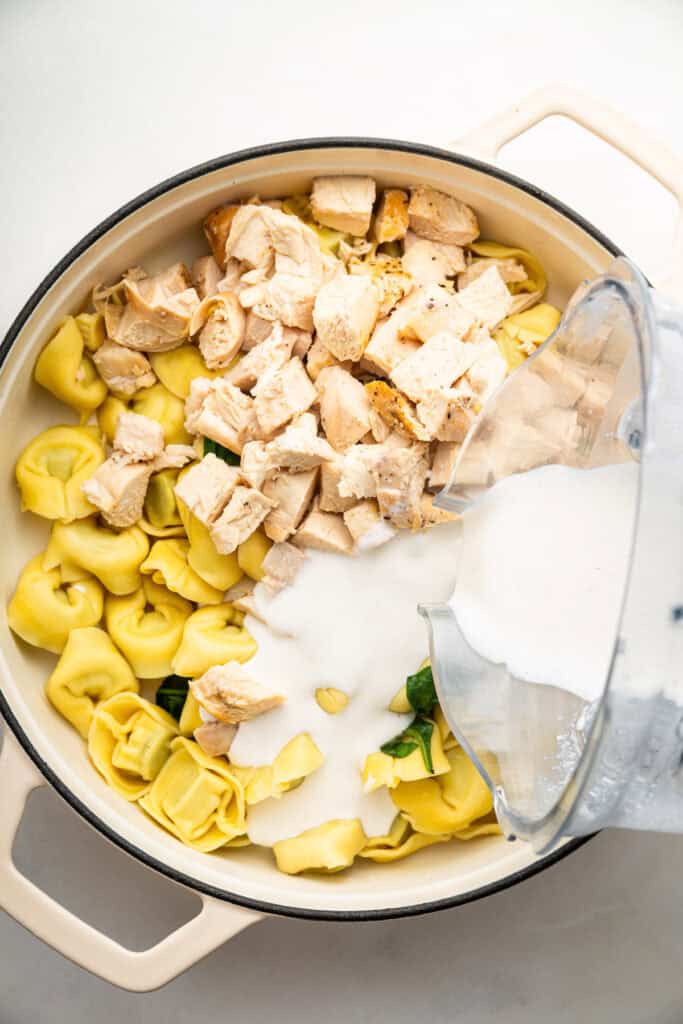 Pouring cottage cheese Alfredo into skillet