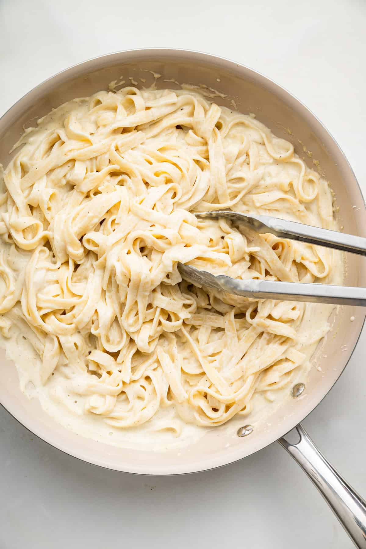 Overhead view of fettuccine with cottage cheese Alfredo sauce in skillet