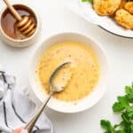 Spoon stirring honey mustard dipping sauce in bowl