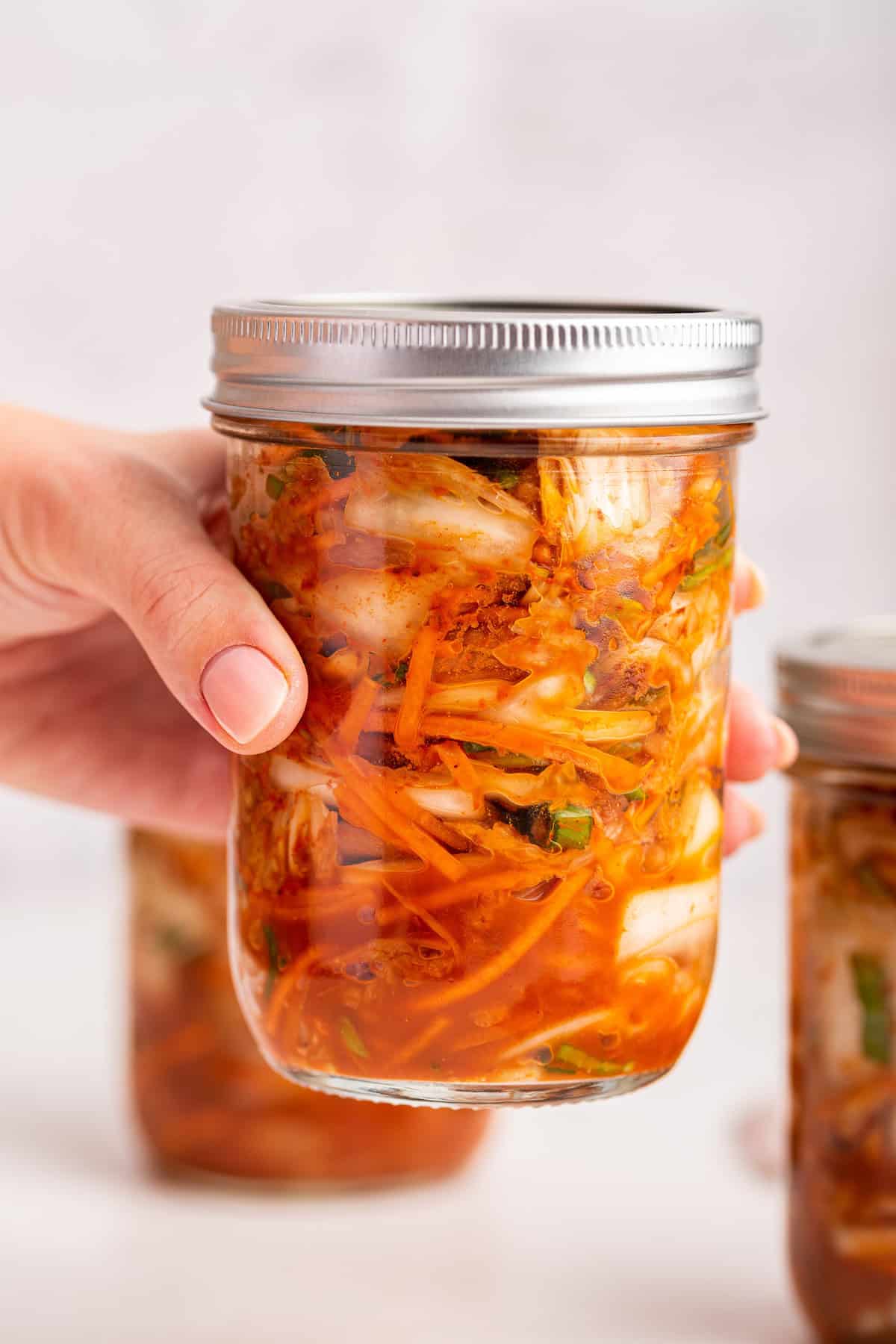 Hand holding jar of homemade kimchi