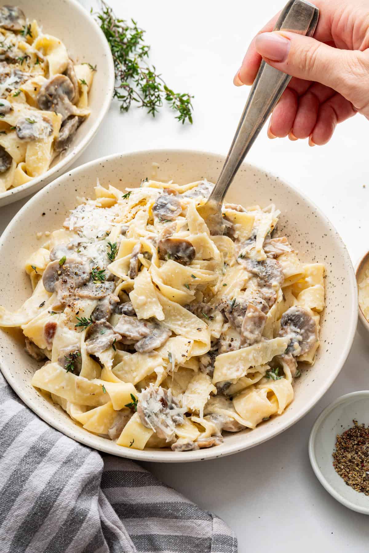 Fork digging into bowl of creamy mushroom pasta