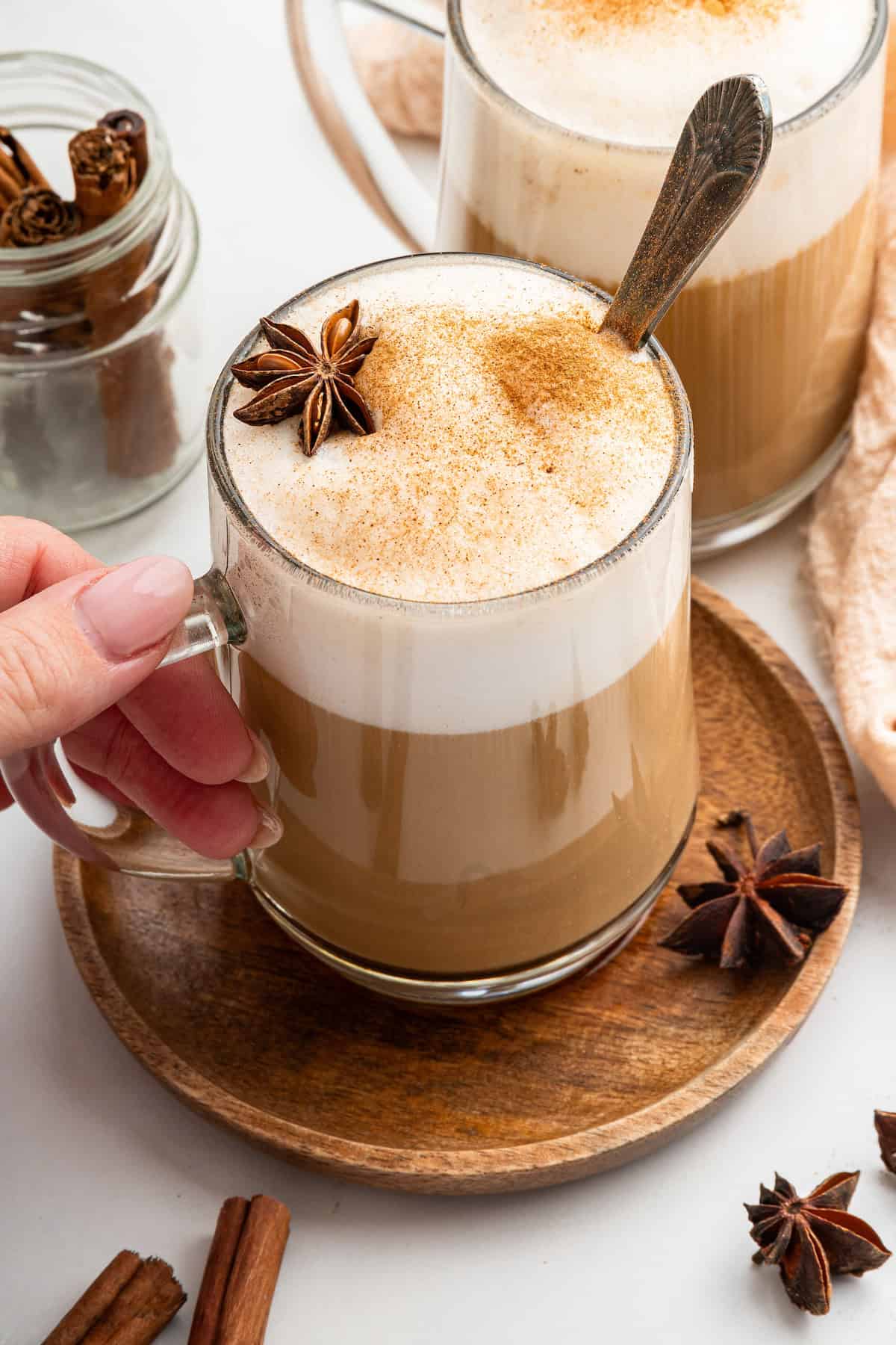 Hand holding dirty chai latte in glass mug