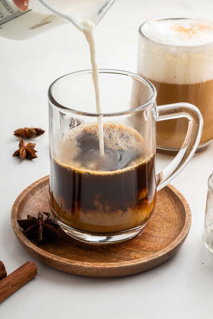 Pouring steamed milk into mug for dirty chai latte