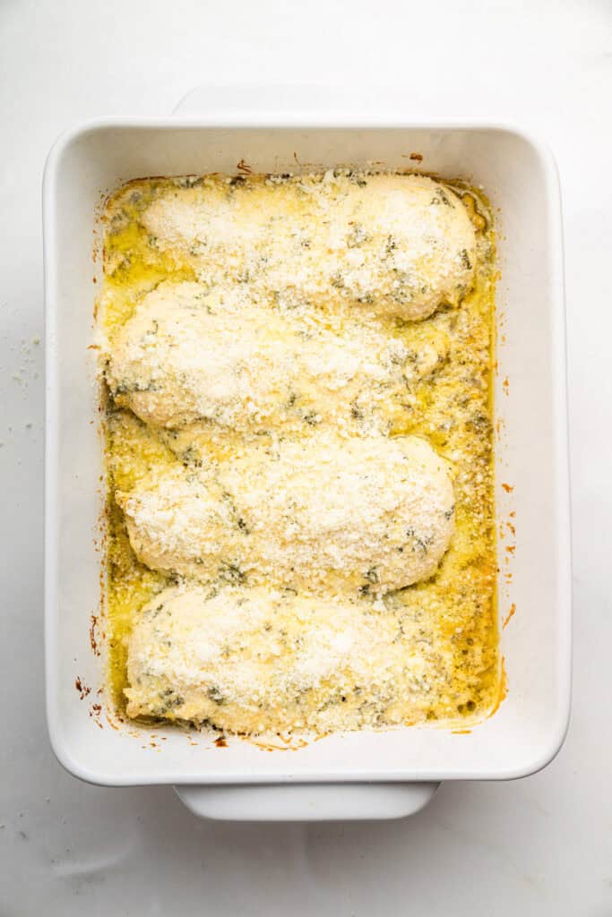 Adding cheese to Italian Dressing Chicken in a baking dish.