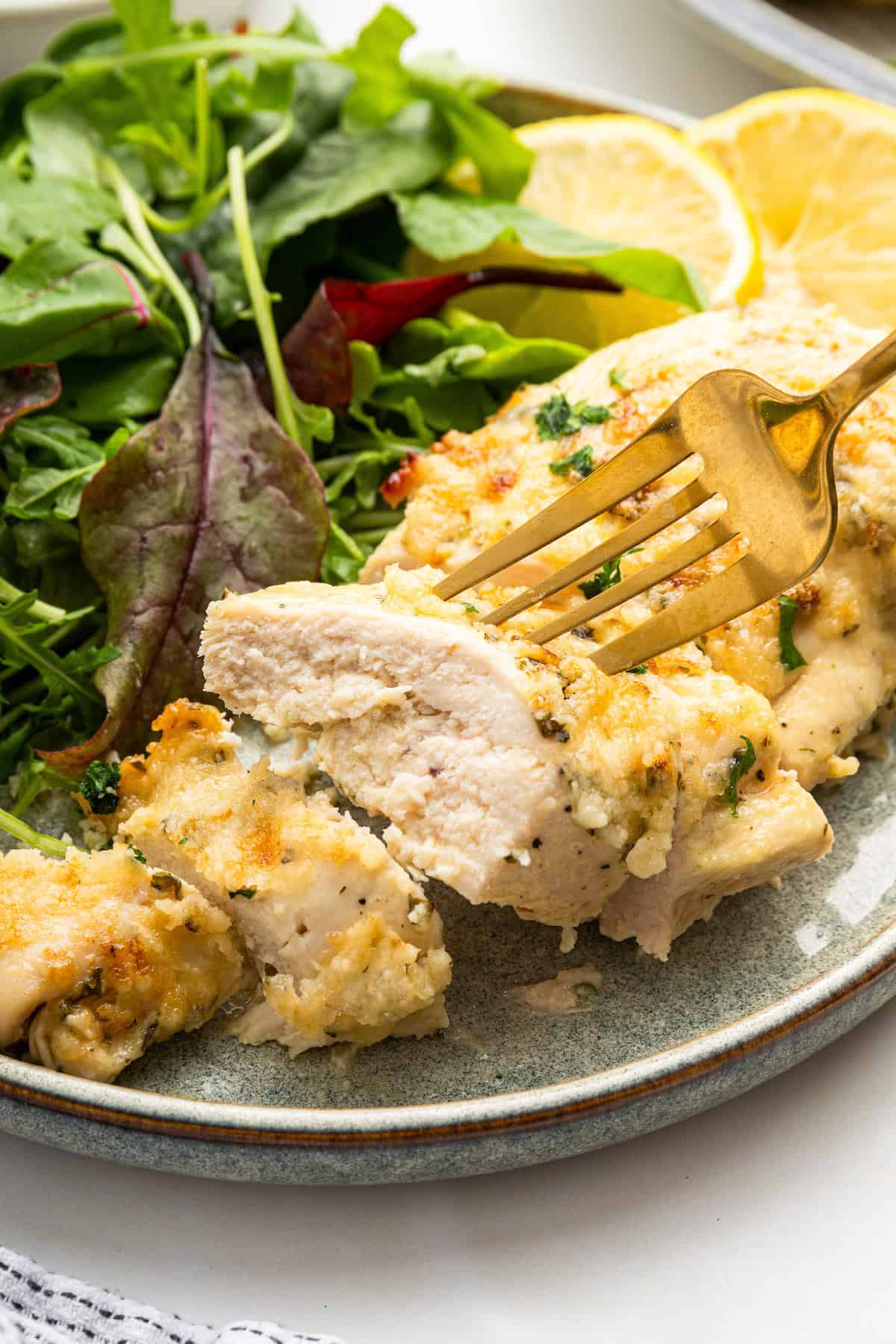 Sliced Italian Dressing Chicken on a plate next to salad.