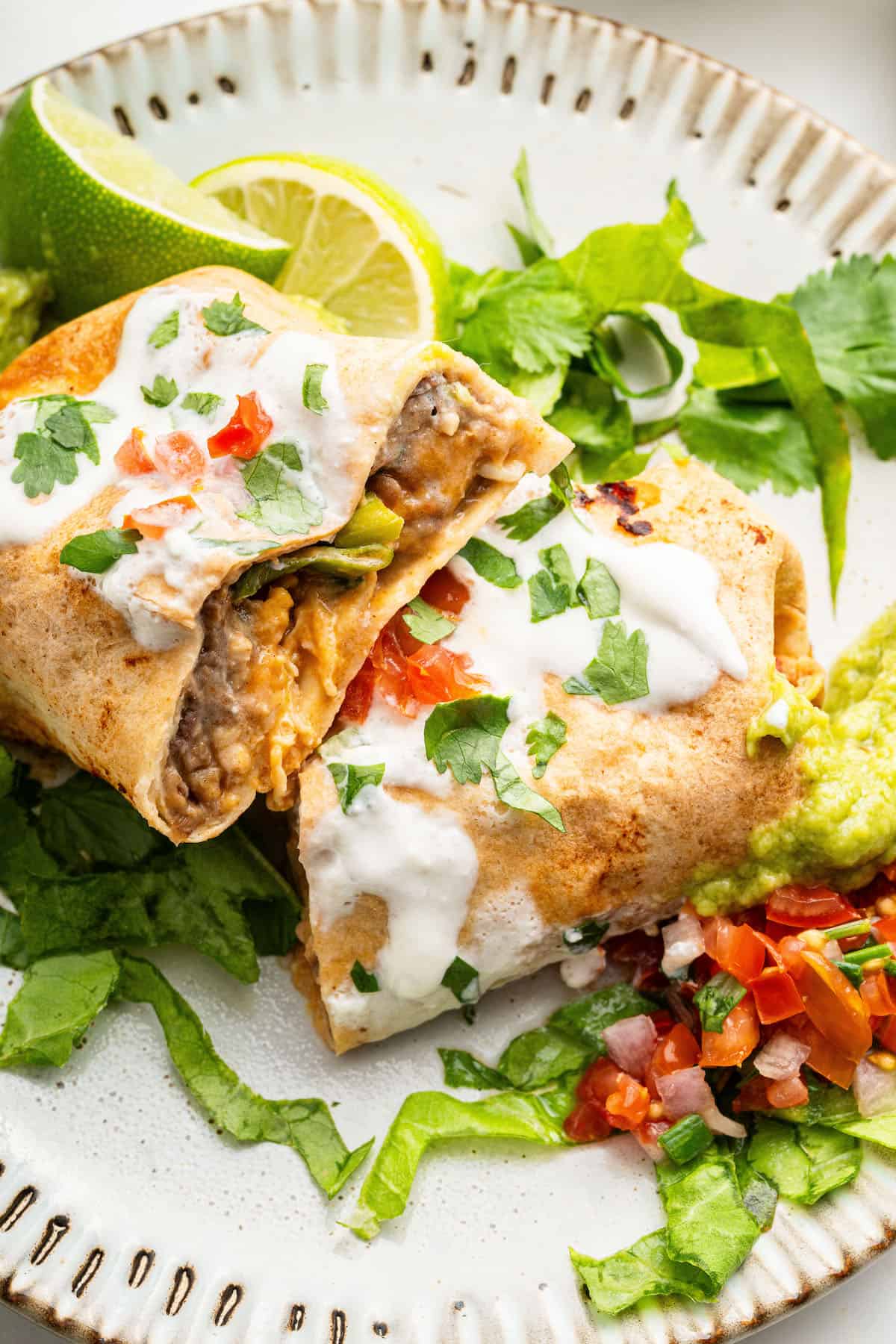 Air fryer chimichanga cut in half on plate with toppings