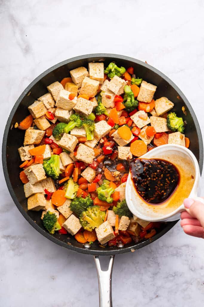 Pouring sauce into tofu stir fry